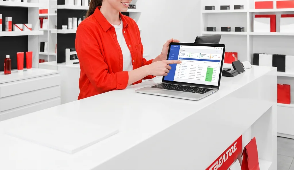 A store manager pointing at the Sveltos dashboard on a laptop, on the shop counter